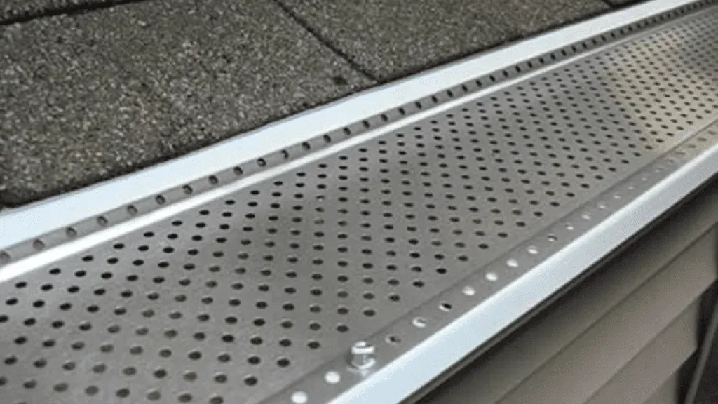 Perforated gutter guard installed along a shingle roofline